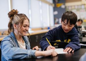 Teacher working with student holding pencil