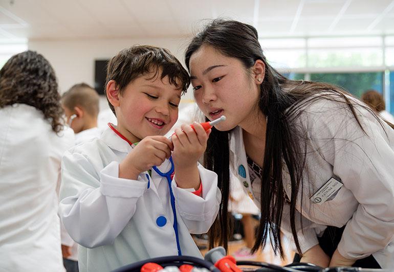 First-year COMP student Katrina Ngo goes over medical equipment with La Verne Science & Technology Charter school kindergarten student Athen Lopez during Mini-Medical School. (Jeff Malet, WesternU)