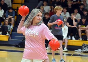 a girl in pink throwing a red ball
