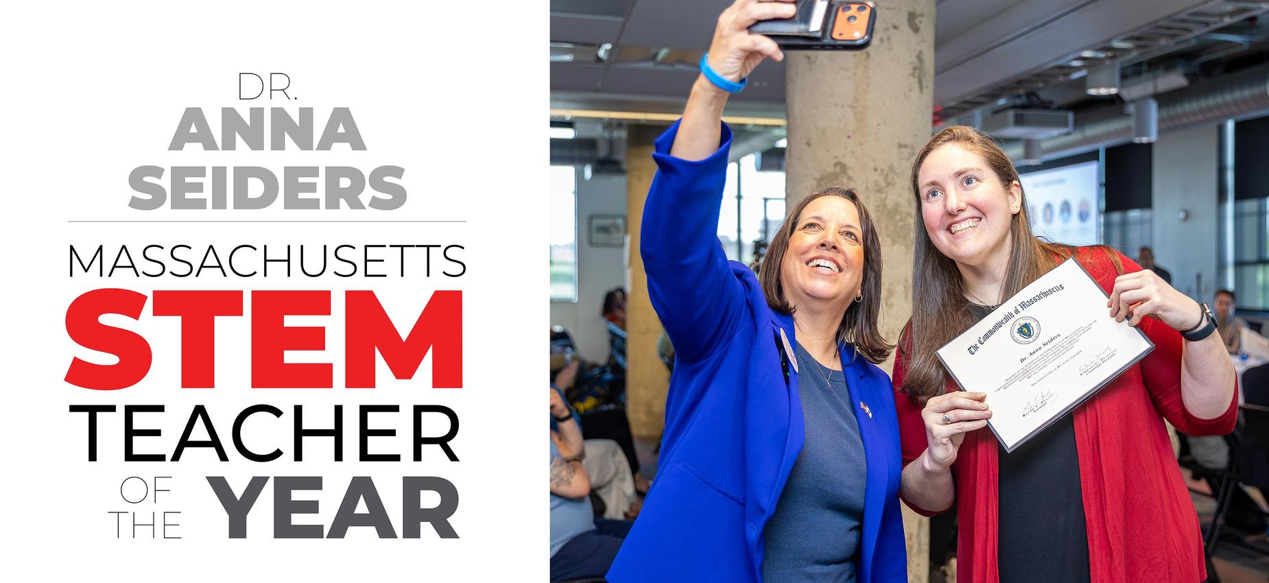 Two women taking a selfie while celebrating a STEM award in a modern office.