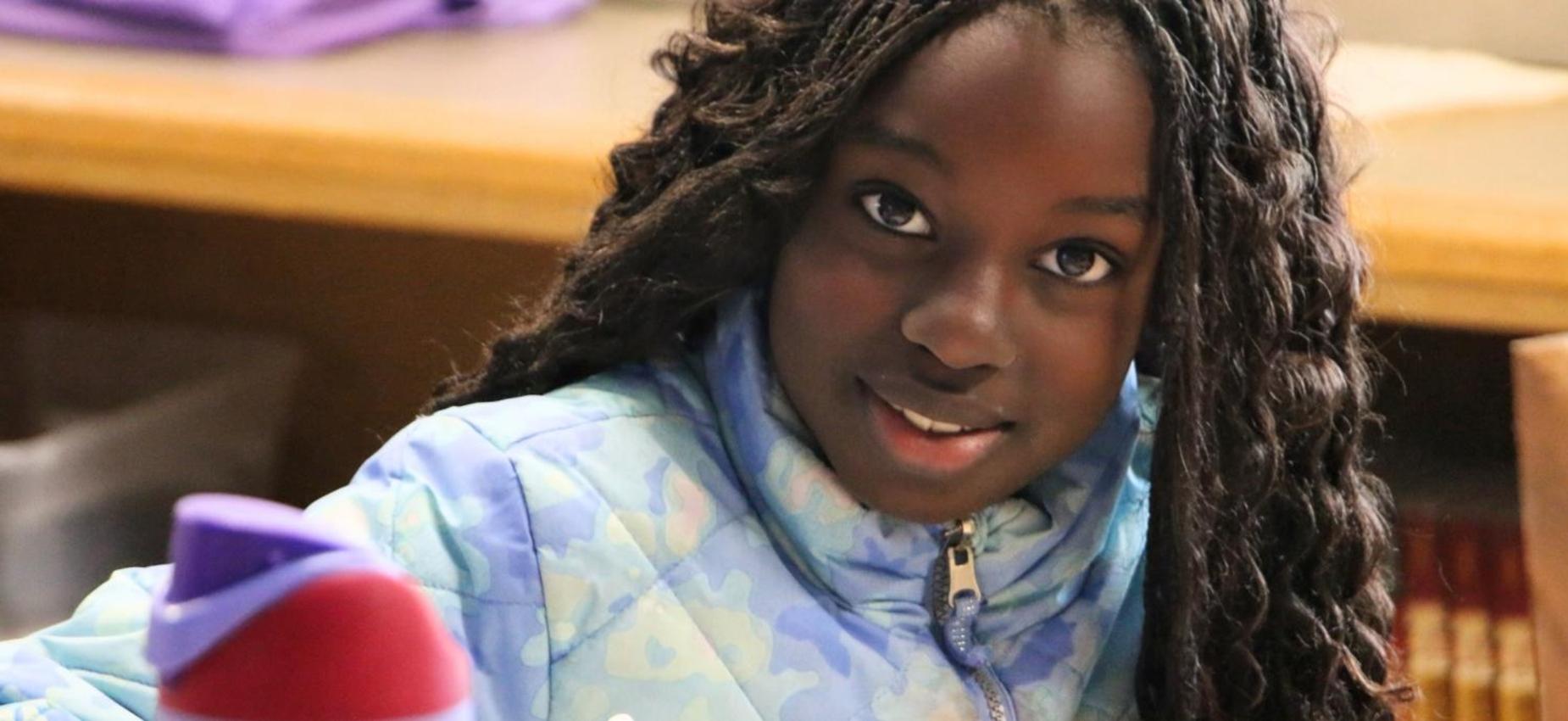 Girl with braids focused on her work in a classroom.
