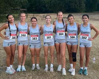 Seven female athletes in athletic gear standing together on a field.