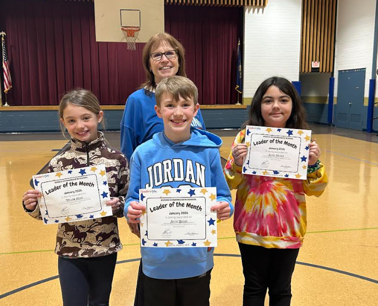 three students holding certificates in gym with principal