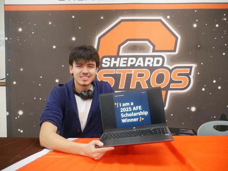 Carlos Castillo smiles while holding laptop
