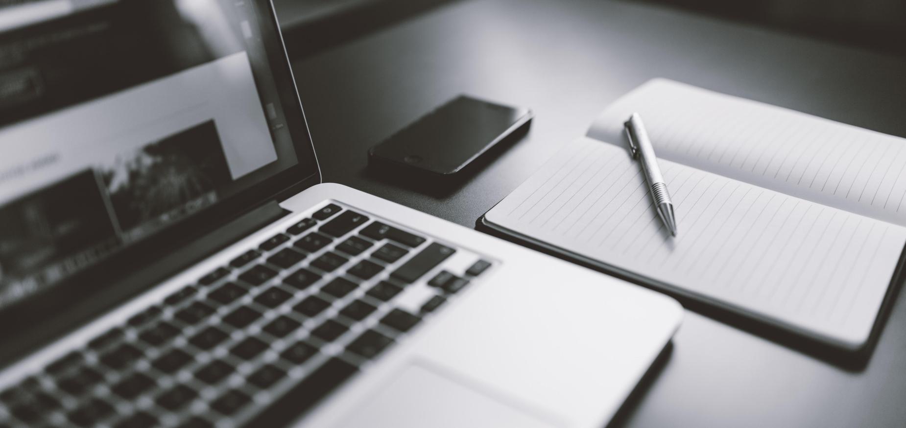 laptop, notebook and pen and cell phone on desk