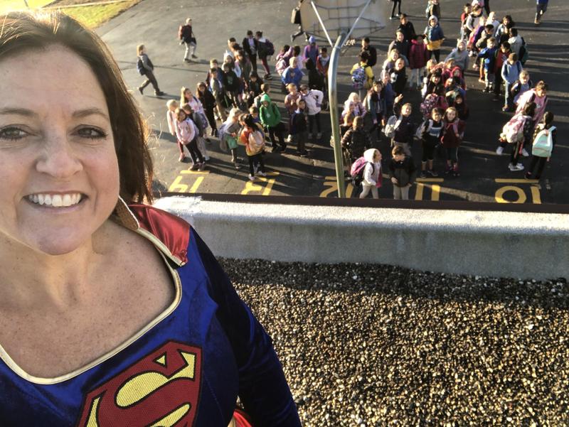 Principal Fergus as Super Girl on top of school with students looking up