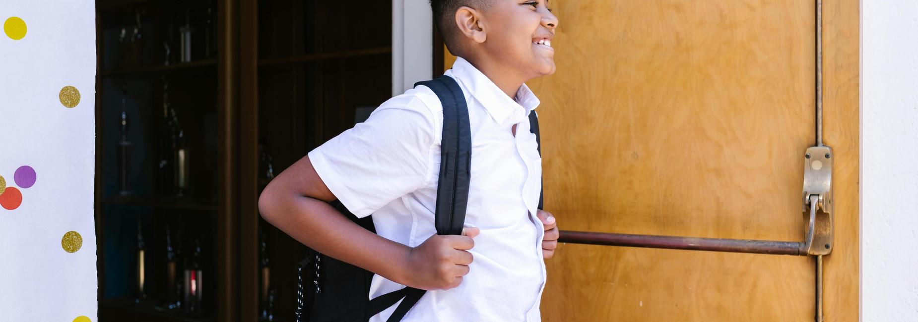 student smiling walking out of school building