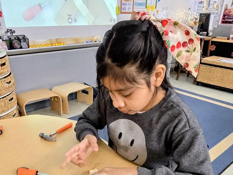 Girl focused on building a model at a classroom table.