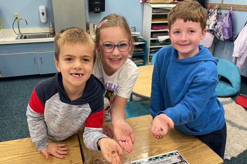 Marcus Mays, Adelyn Schmidt, and Santino Loffredo hold worms from the compost
