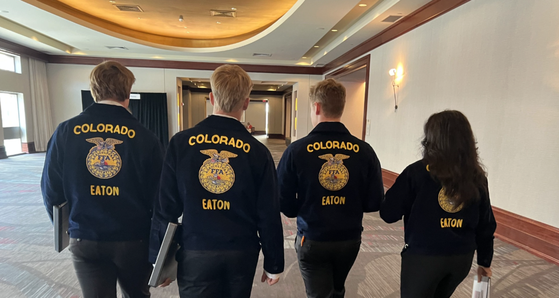 Four students in FFA jackets walking in a hallway.