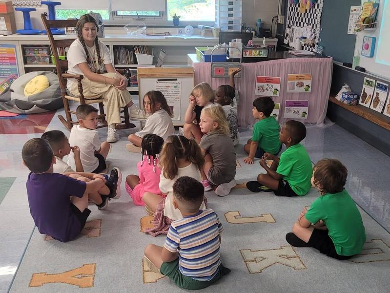 students sit on the carpet for a lesson with their teacher at RES