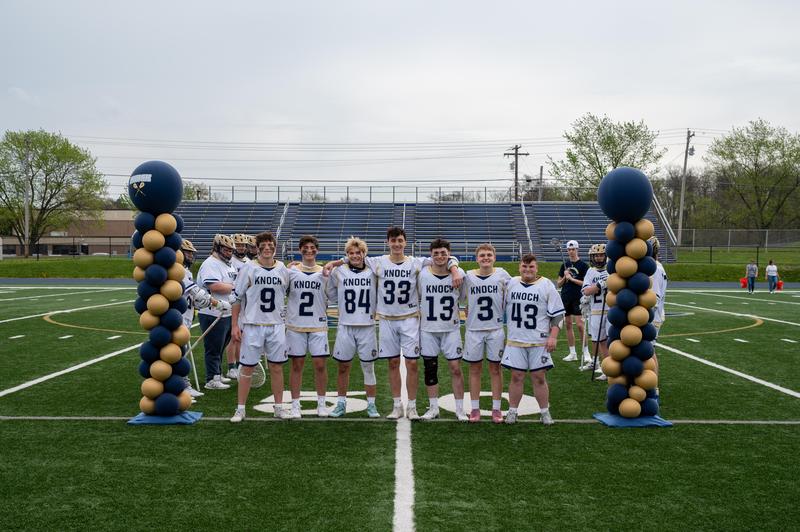 boys in lacrosse jerseys between two balloon columns
