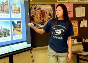 Student giving a talk about various travel destinations from a slideshow.
