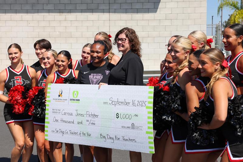 carissa jones fletcher with a giant check and cheer team