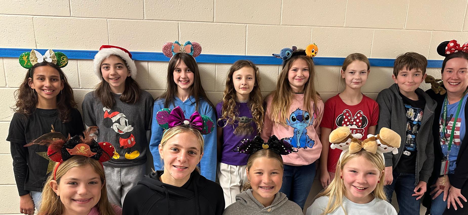 A diverse group of children and adults wearing festive headbands with characters and decorations.