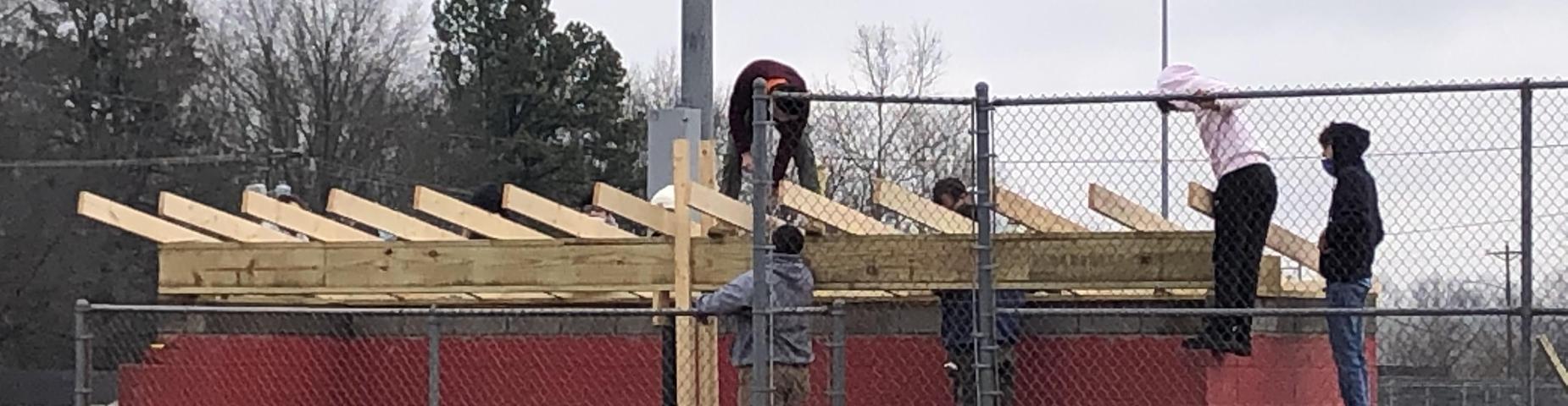 Mr. Hutchins shop class working on putting a new roof on the softball dugouts.