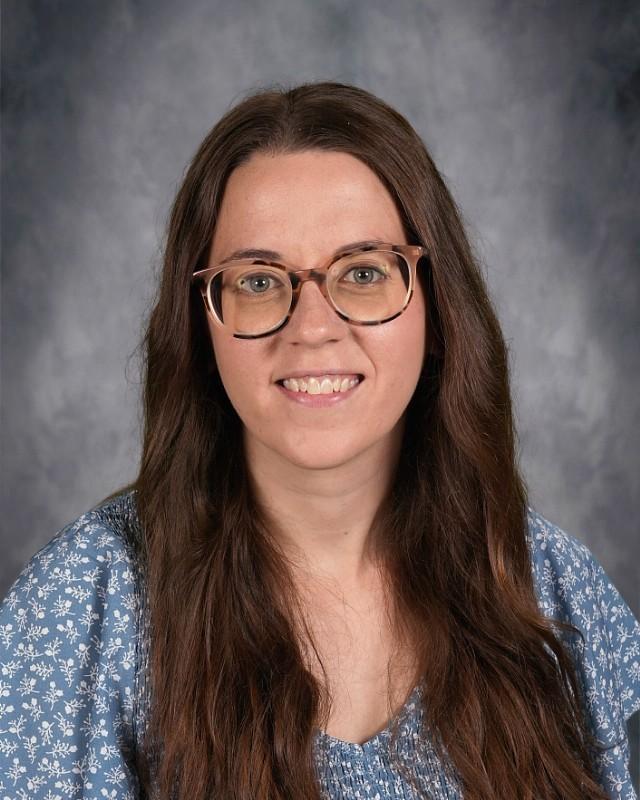 Smiling woman with long brown hair wearing glasses and a pink top.
