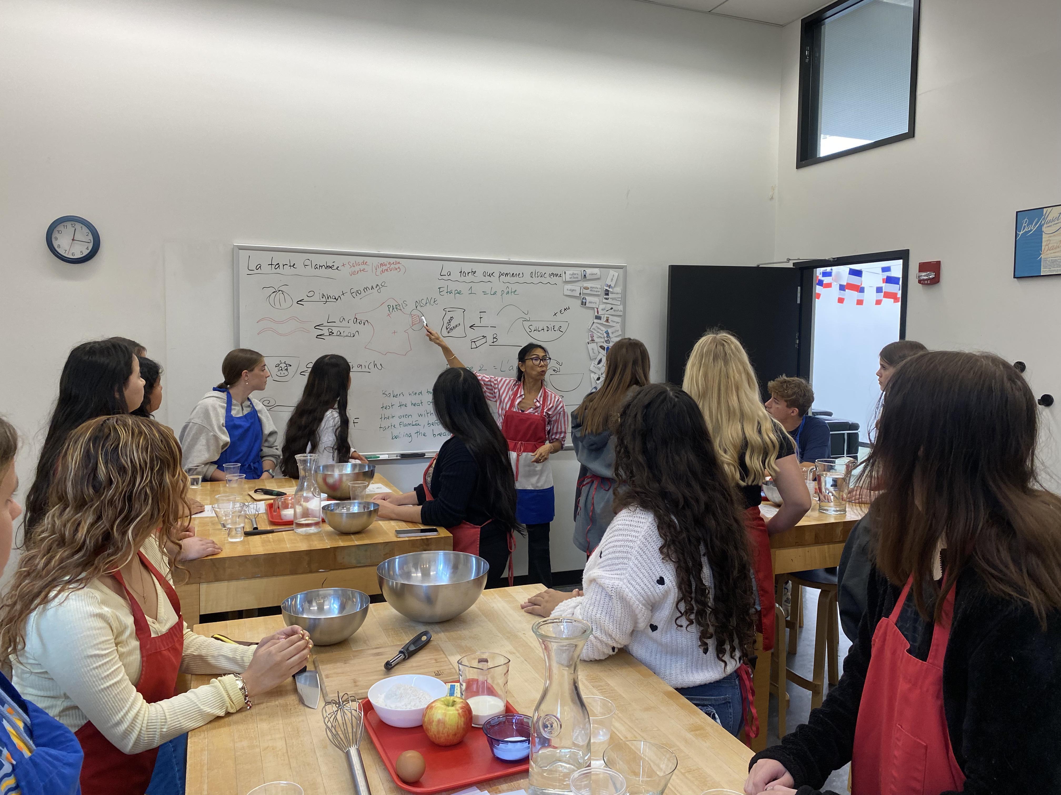 Group cooking class with students preparing recipes at a kitchen workspace.