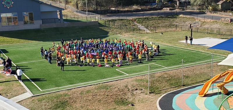 Image shows scholars standing in the shape of the Mandela Sun Logo