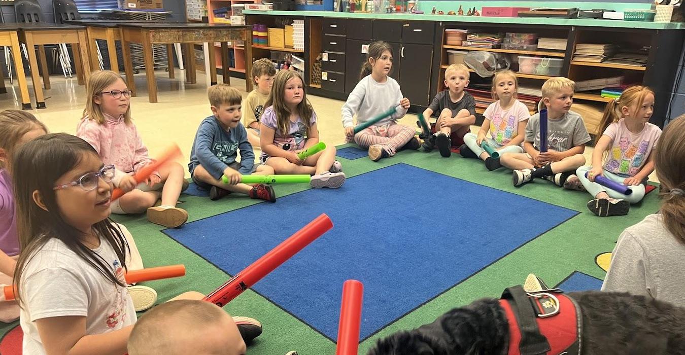 Children sitting in a circle with colorful instruments, engaged in a music activity.