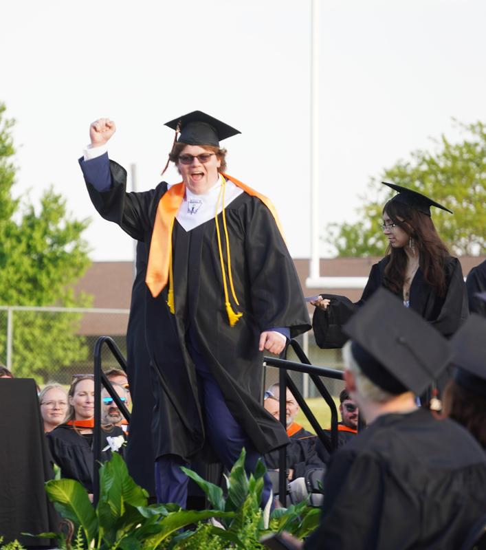A graduate raises his fist in celebration.