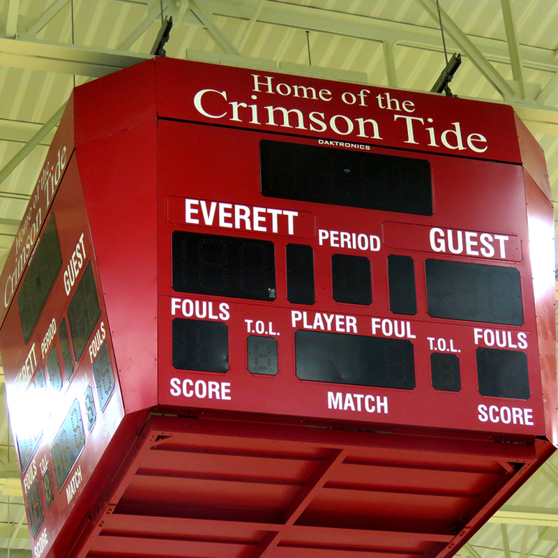 A four-sided scoreboard hanging from the top of Everett's gym, with the words