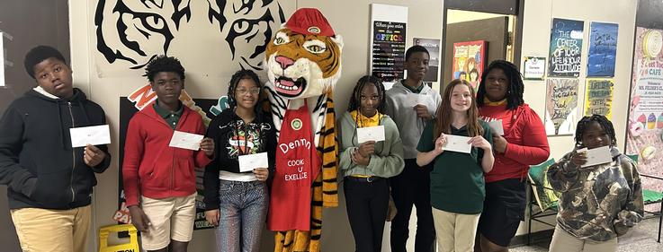Group of students posing with a tiger mascot, all holding envelopes.