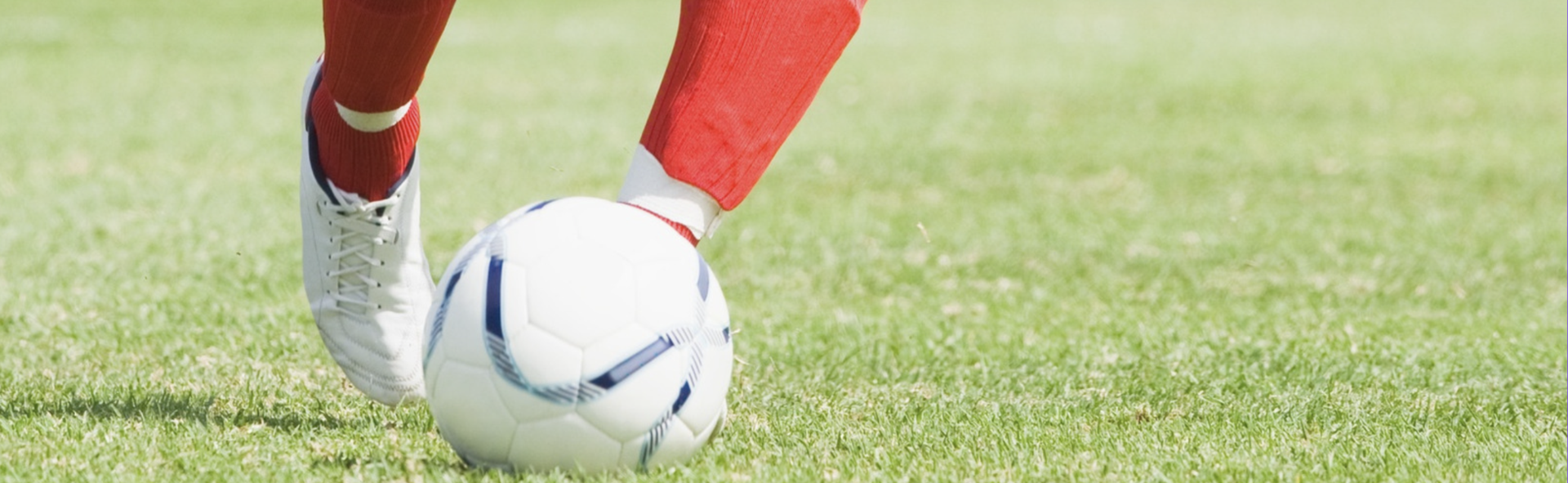 A person wearing red socks kicks a soccer ball