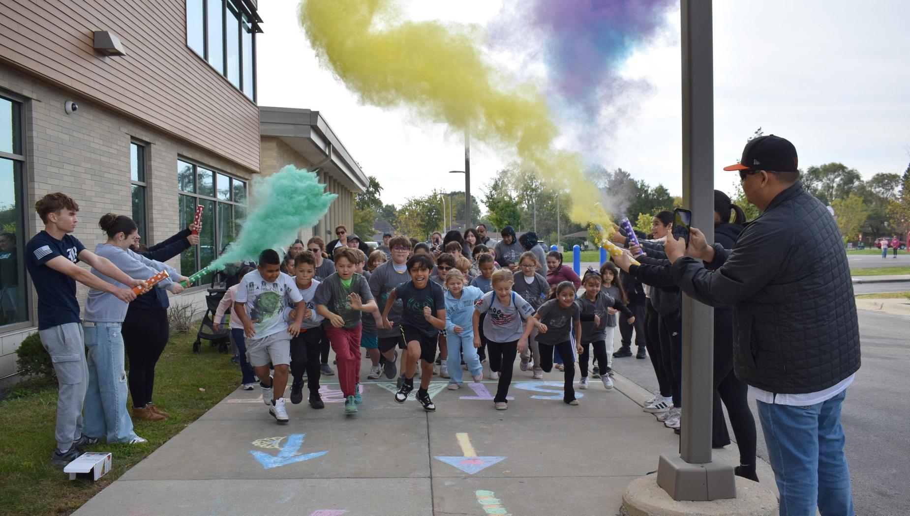 A group of children running outdoors, celebrating with colorful smoke bombs.