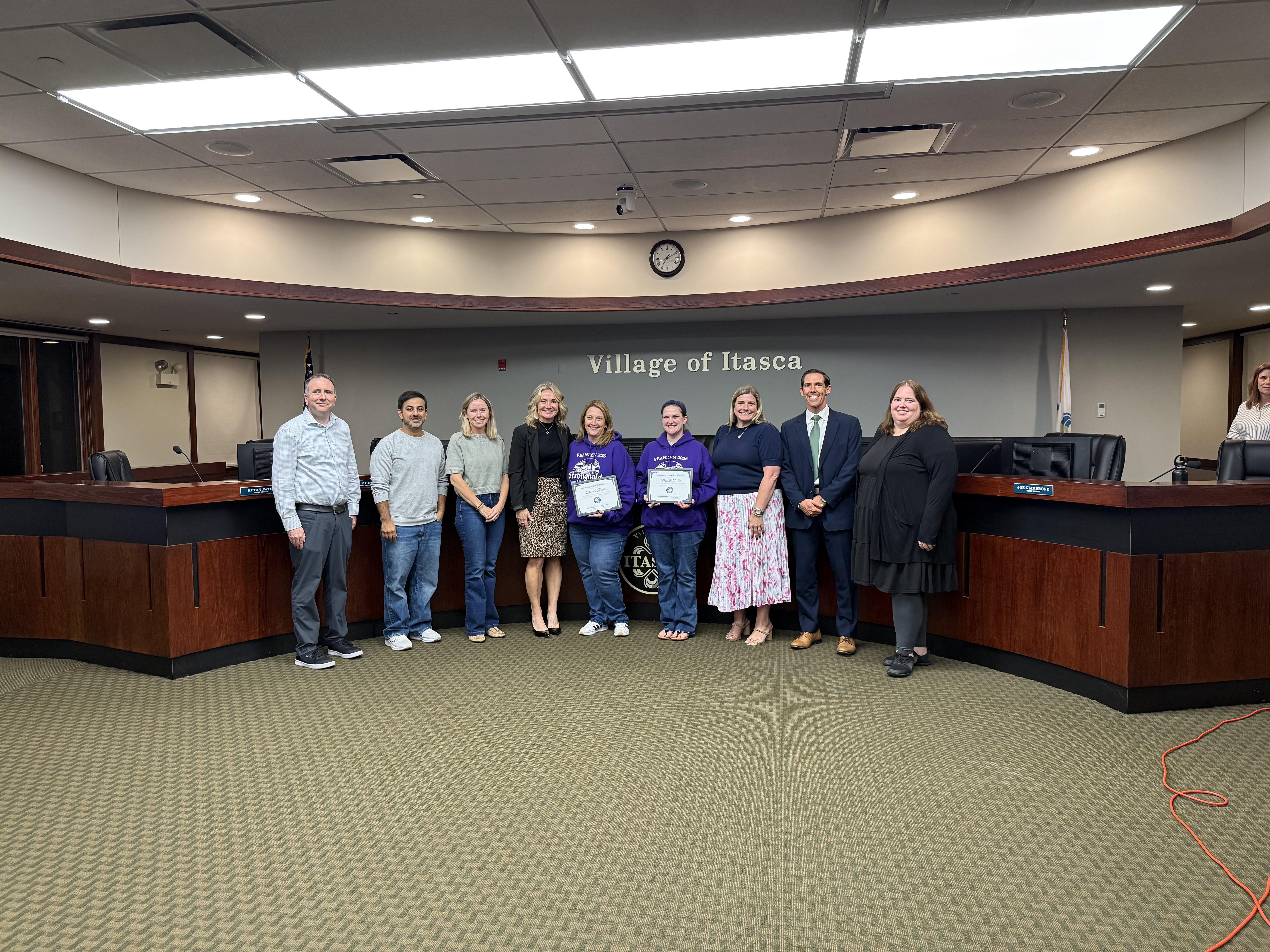Group stands and smiles for an award at the october board meeting