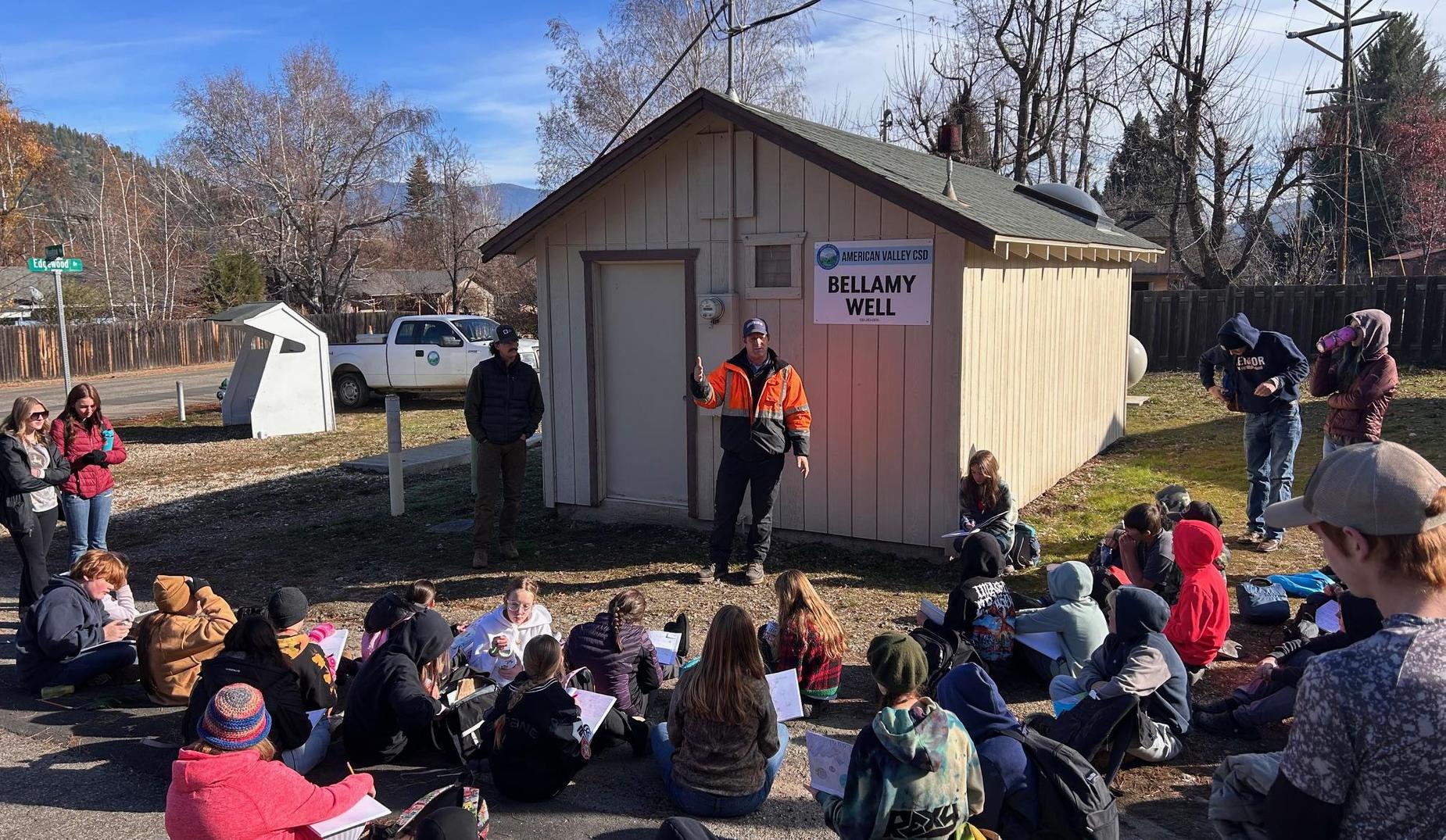 6th graders sit outside a municipal well house learning about where their water comes from.