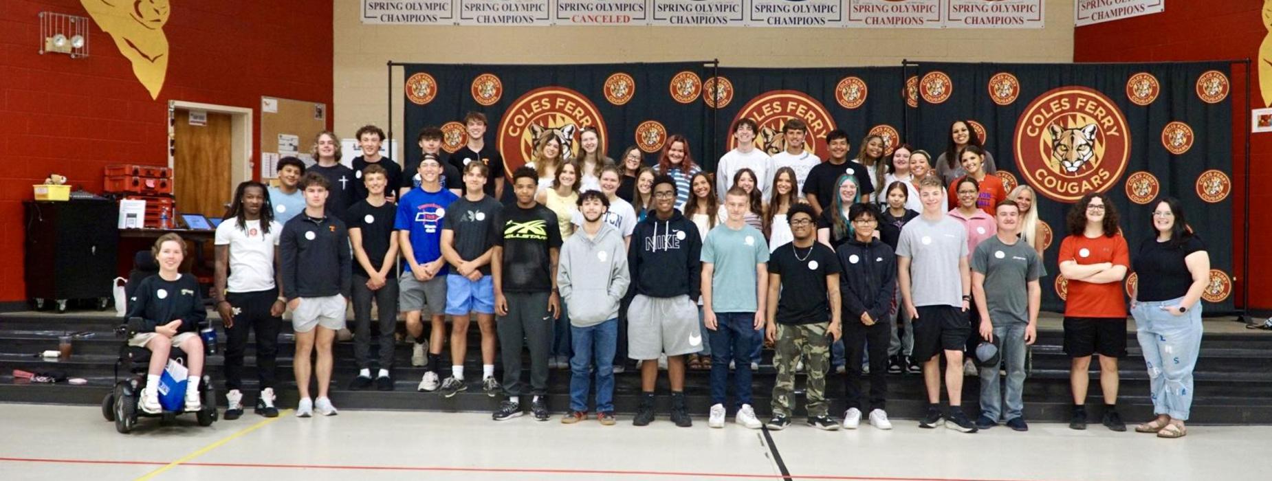 Group of diverse students posing together in a gymnasium setting.
