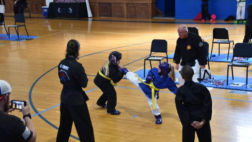 Martial arts tournament with participants sparring in a gym setting.