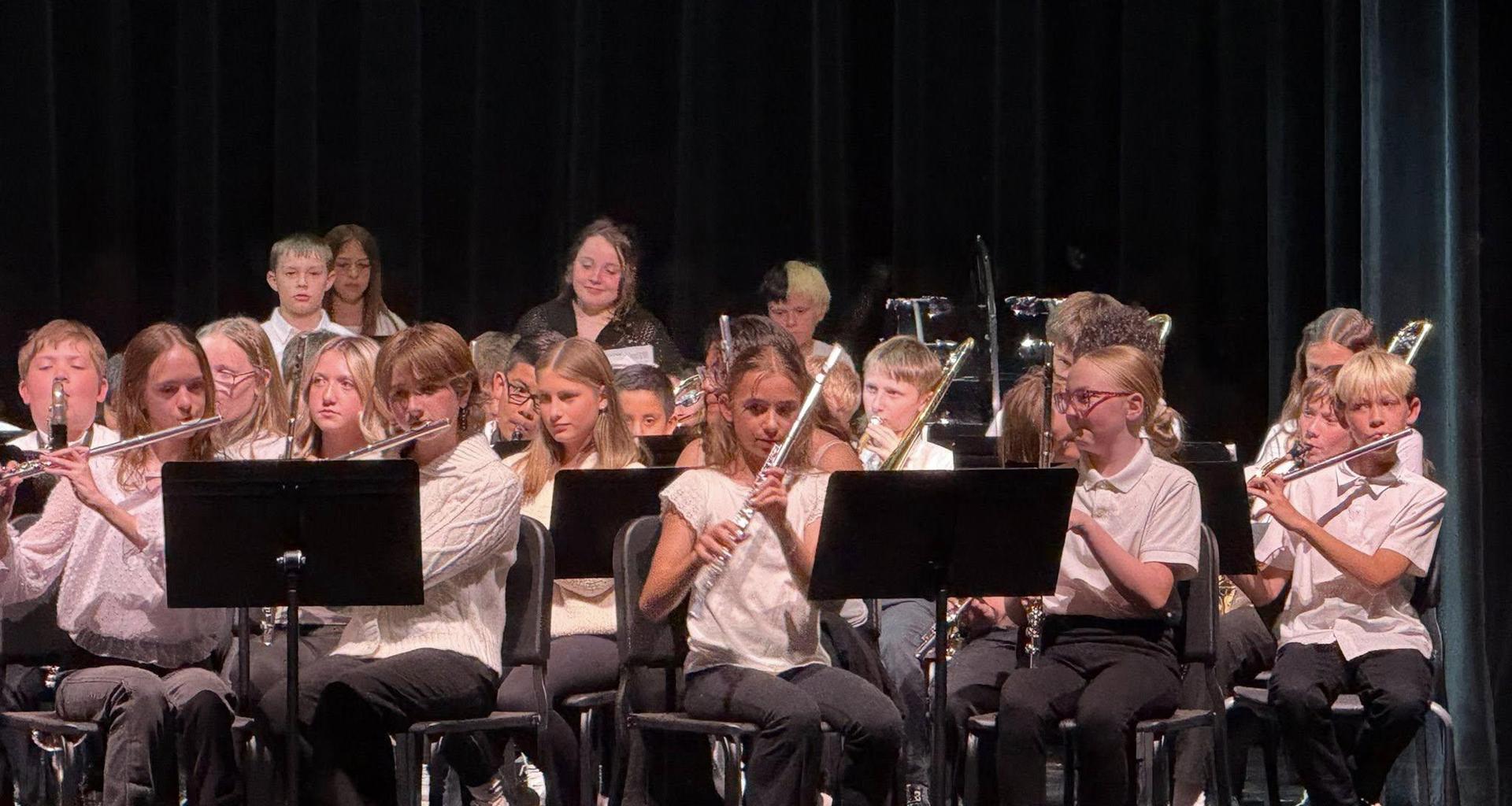 A group of young musicians playing flutes in a school concert setting.