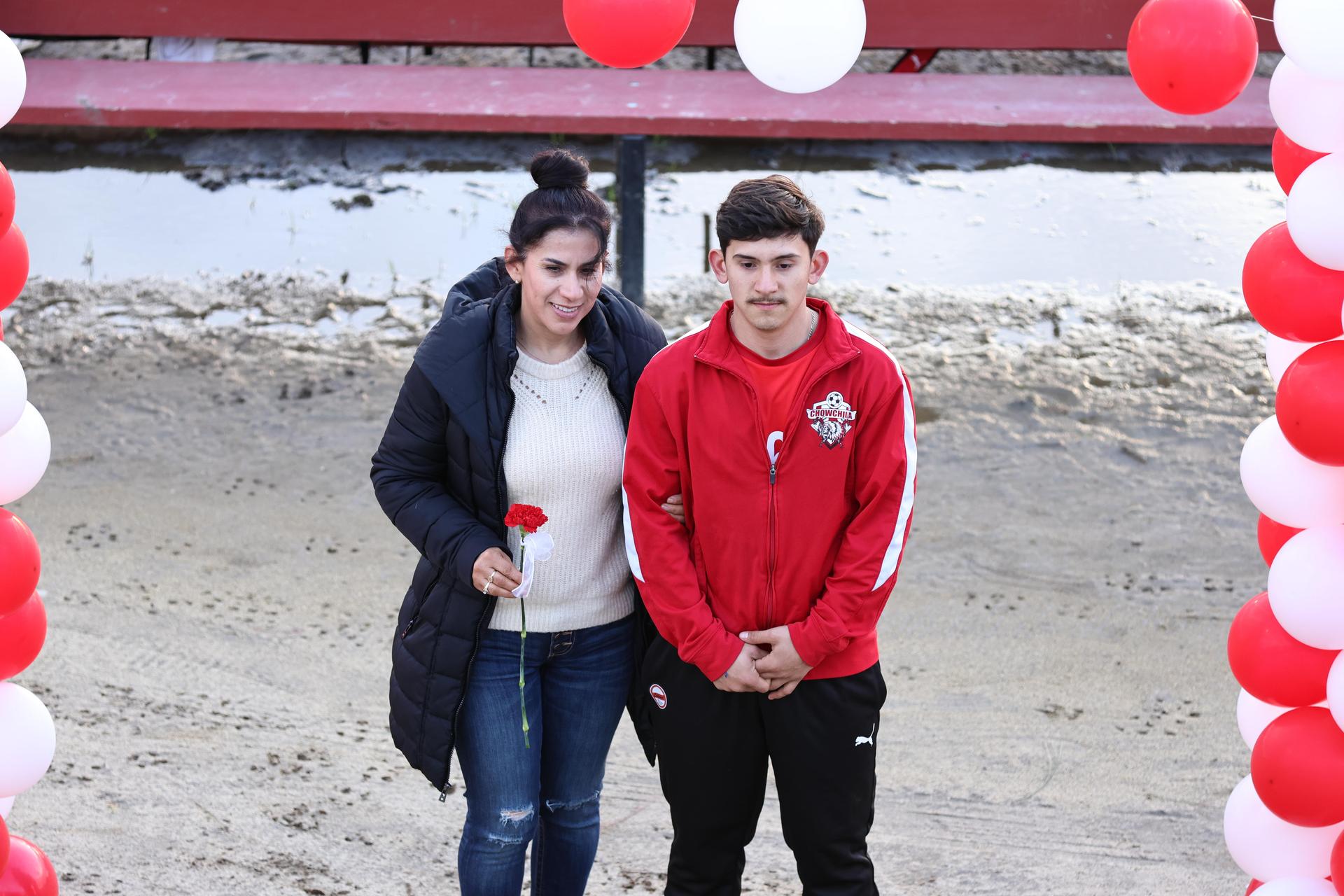 seniors and their escorts posing beneath a balloon arch