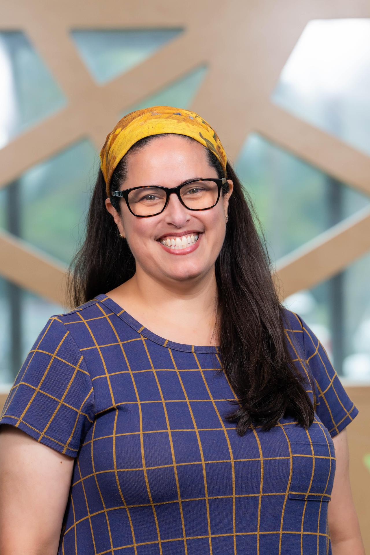 Gussie Singer with glasses and blue blouse and light blue headband smiling