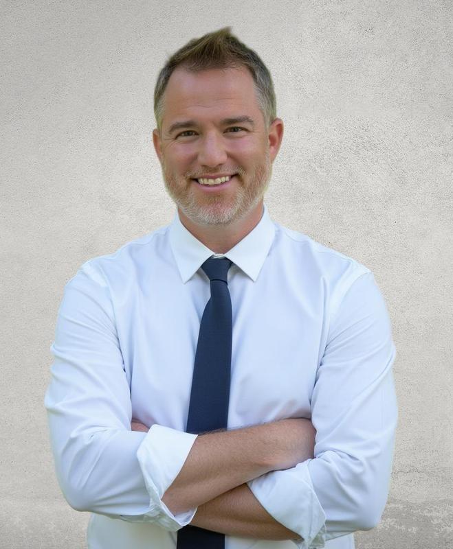 The leader of the school standing with his arms folded.