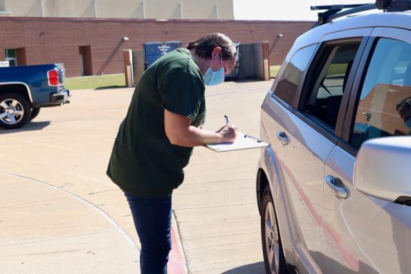 woman writing on clipboard standing beside a minivan