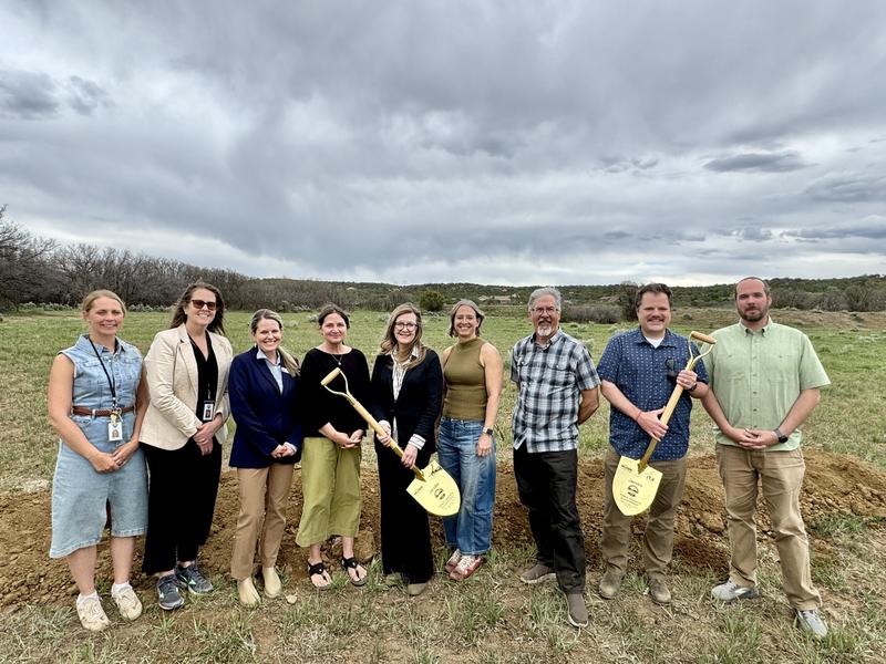 Group of people stand in field before groundbreaking