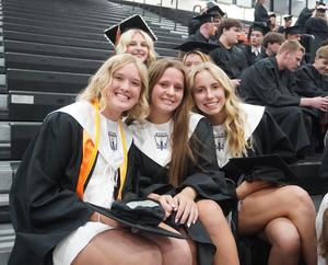 Three graduates pose before graduation.