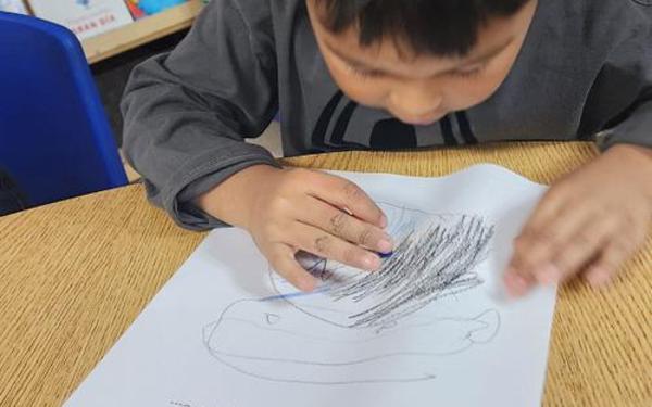 Boy drawing on a piece of paper.