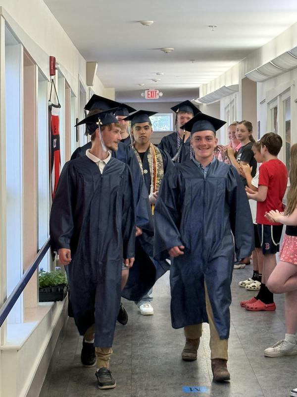 Seniors walking down the hallway in cap and gown