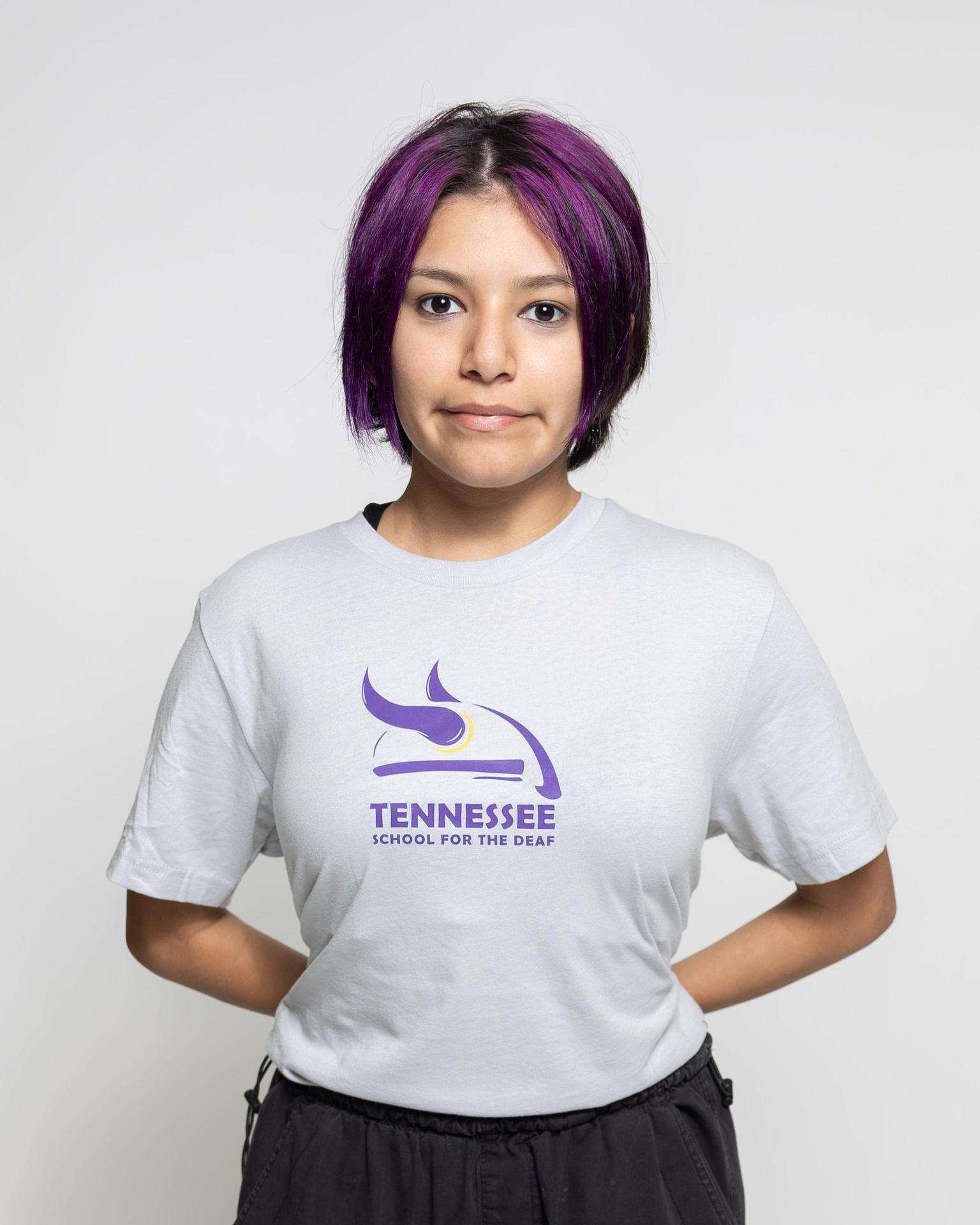 Youth wearing a gray t-shirt with Tennessee School for the Deaf logo, hands behind back.