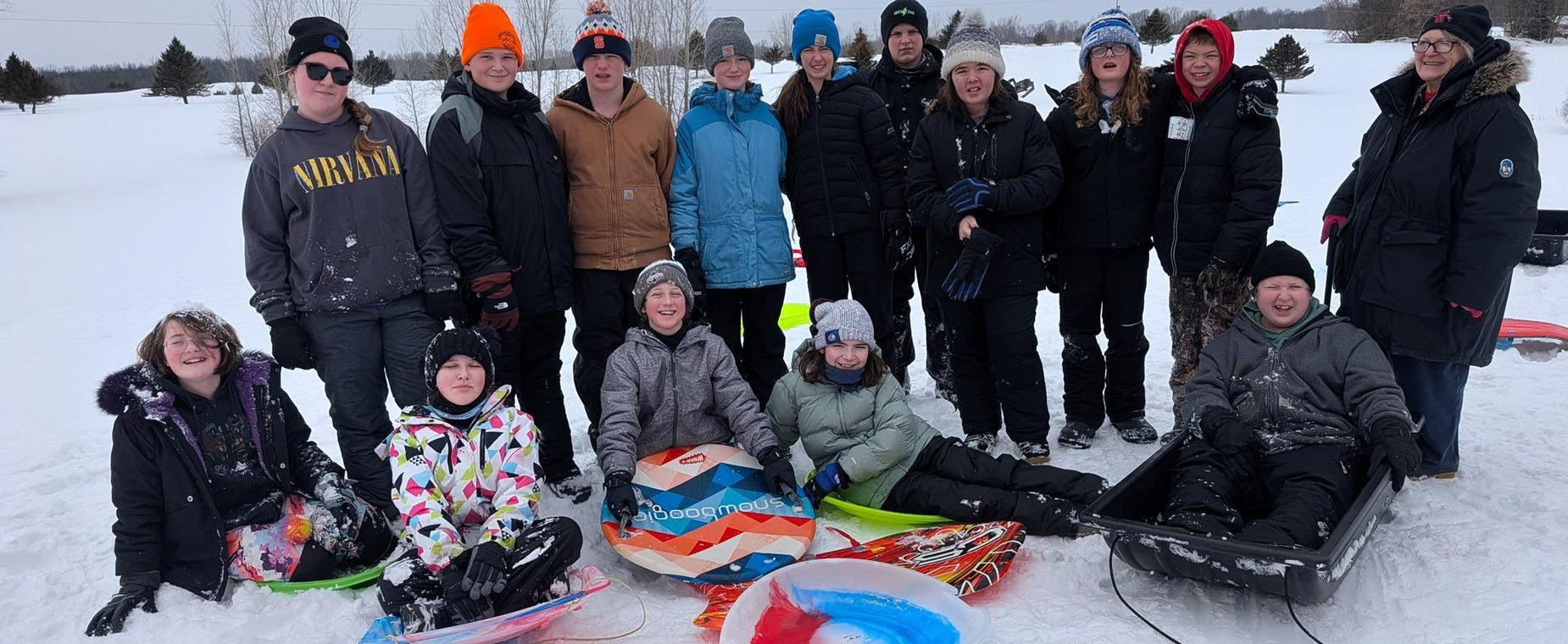 students outdoors with snow sleds