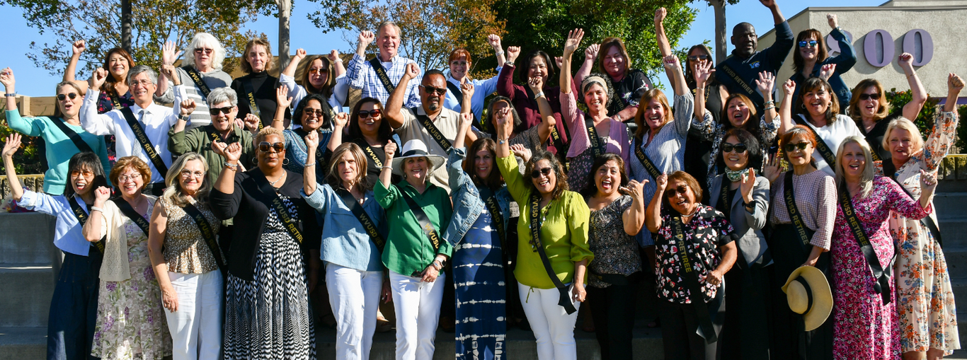 Energetic group of people cheering and waving hands outdoors.