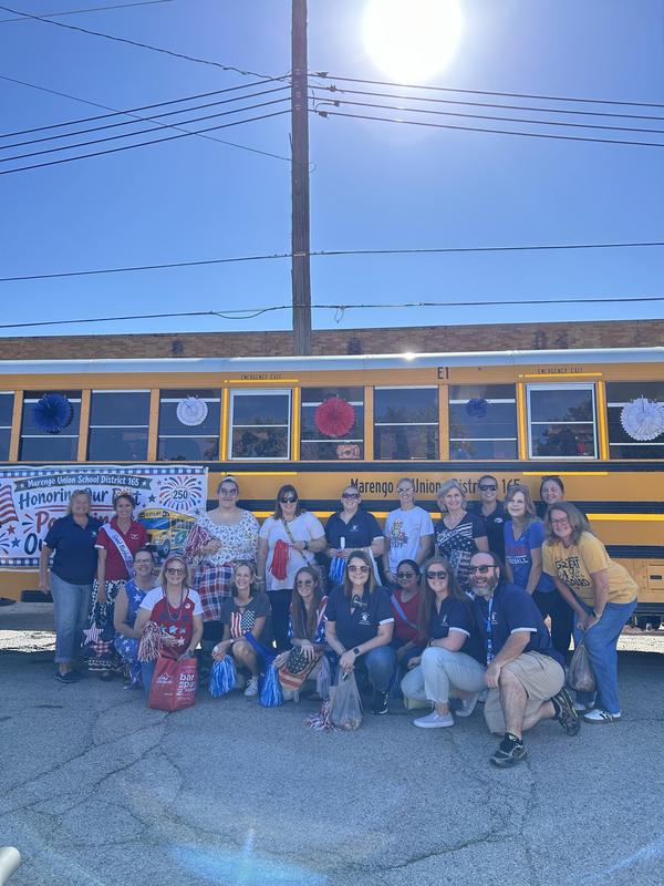 District 165 staff gather alongside the decorated school bus at the Settler’s Day Parade.