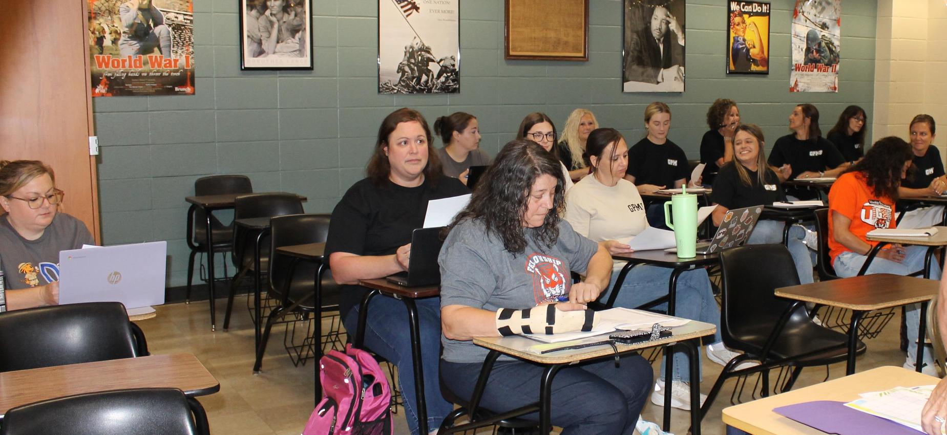 Classroom scene with students seated at desks, focusing on a speaker.