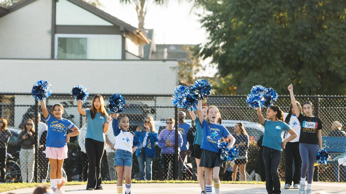 Cheerleaders performing with pom-poms in front of a crowd at an event.