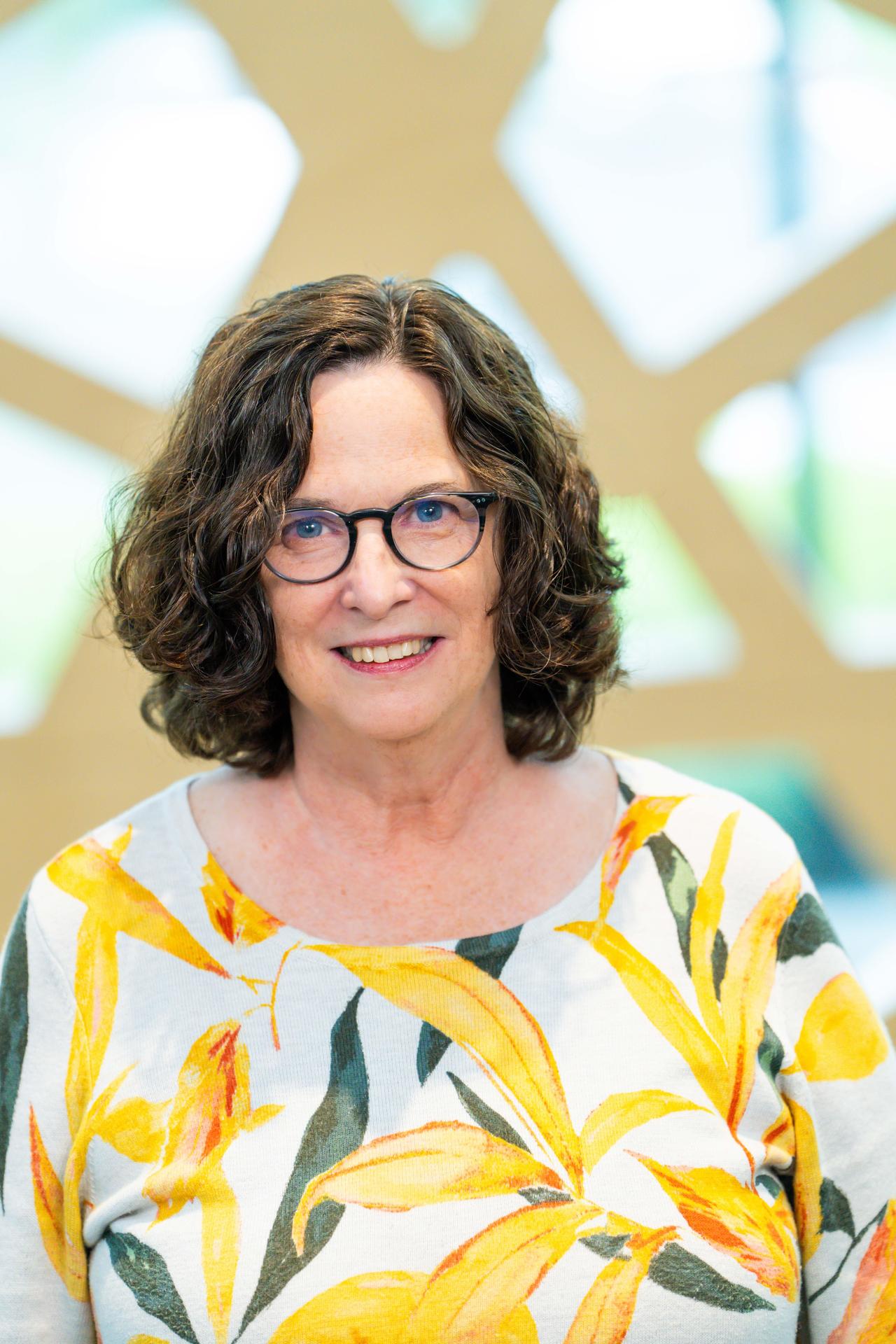 Janet Keane with wavy brown hair and glasses