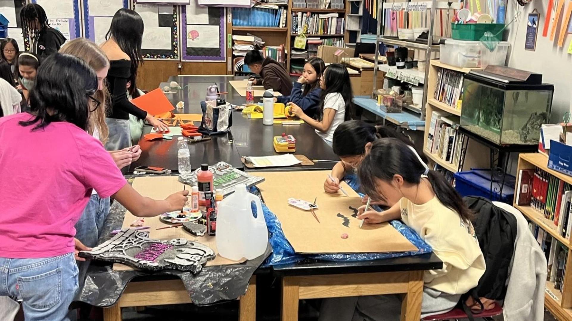 Students engaged in art projects at a classroom table.